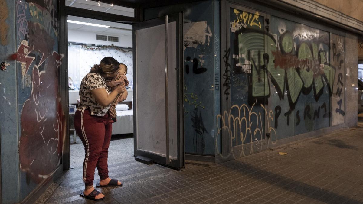Diamata Gheorghe arropa a su hija Raisa, en la antigua oficina de un banco ocupada donde vive con el resto de su familia