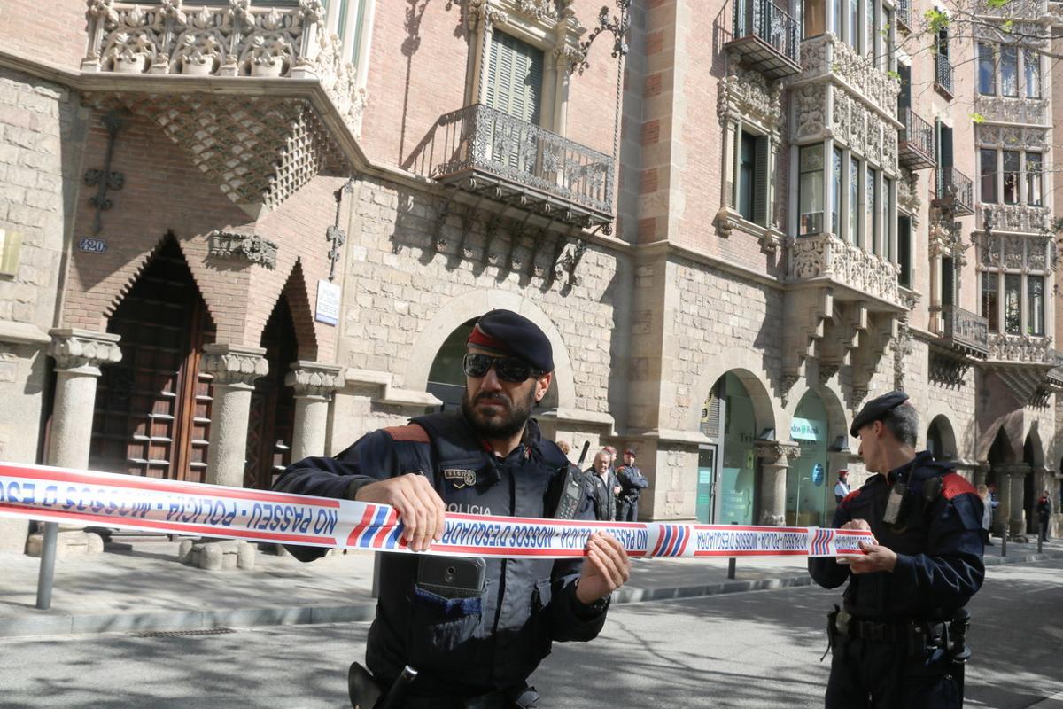 Dos agentes de los Mossos acordonan la zona mientras la Guardia Civil inspecciona la sede del Diplocat, durante un registro el pasado 12 de abril.
