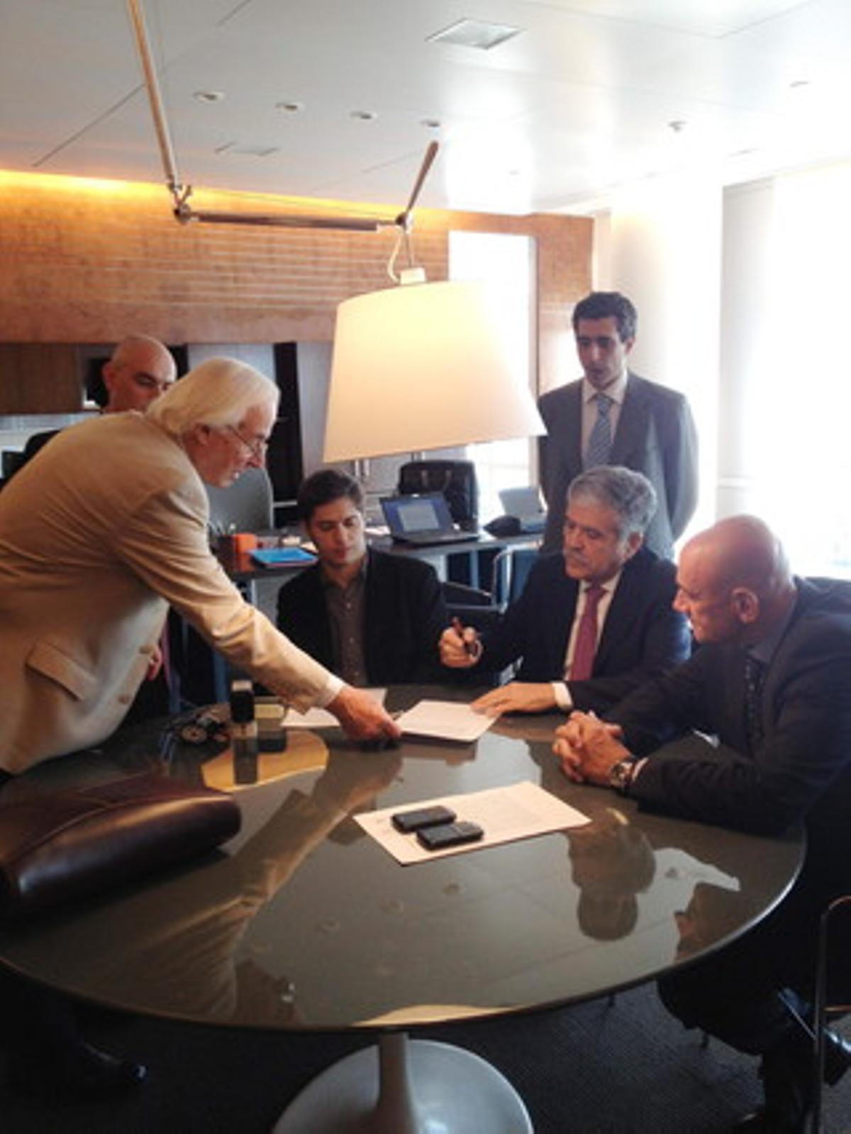 El ministro de Planificación de Argentina, Julio De Vido (segundo por la derecha) firma el acta para asumir las funciones de interventor de YPF, acompañado por el viceministro de Economía, Axel Kicilloff (centro), el lunes, en Buenos Aires.
