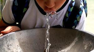 Un niño bebe agua en una fuente de su cole en plena ola de calor en Madrid. 