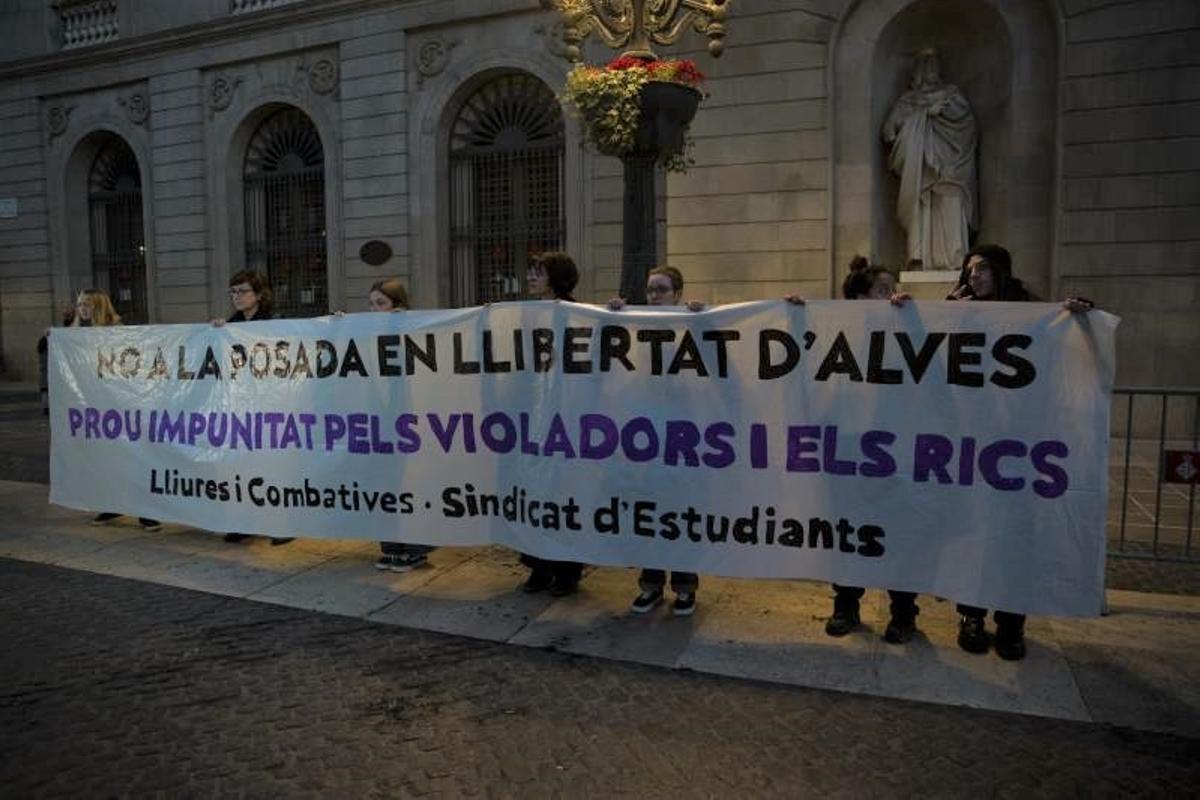Un grupo de personas sostiene una pancarta durante una concentración en contra la petición de libertad de Dani Alves en la plaza de Sant Jaume.