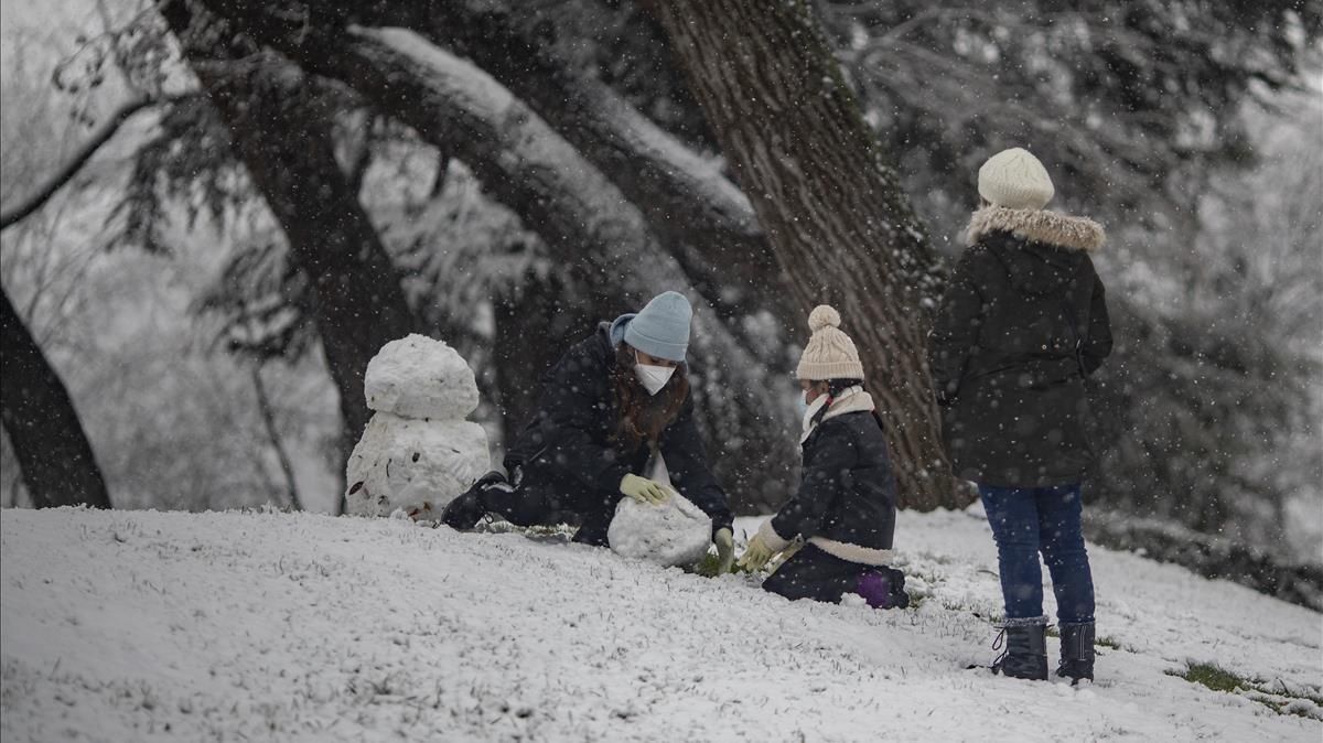 Tres personas juegan con la nieve el parque del Retiro. Tres personas juegan con la nieve el parque del Retiro.