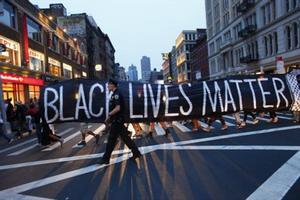 Un policía acompaña la manifestación por la calles de Nueva York del movimiento civil Black Lives Matter (la vida de los negros importa), ayer domingo.