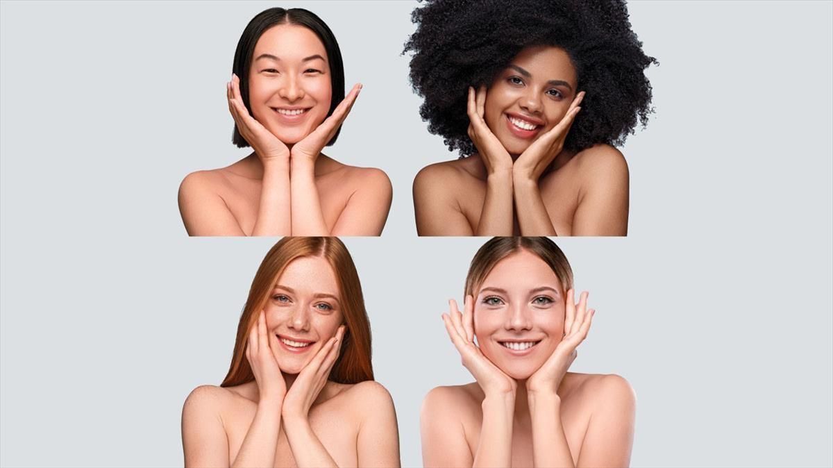 gente The Cool Skin Optimistic multiethnic young ladies touching clean face skin and smiling for camera while representing cosmetology industry against blue background gente The Cool Skin Optimistic multiethnic young ladies touching clean face skin and smiling for camera while representing cosmetology industry against blue background