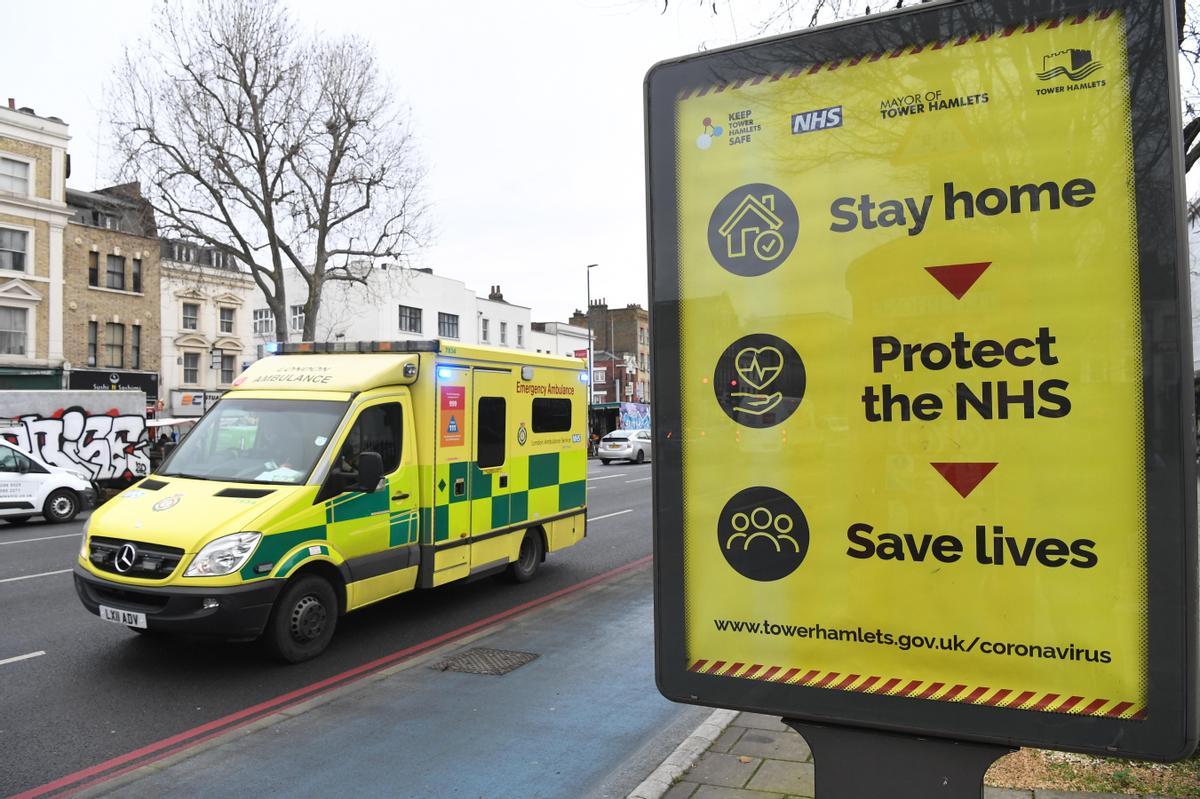 Un ambulancia pasa junto a un cartel urbano con consignas sobre las precauciones contra el covid-19.