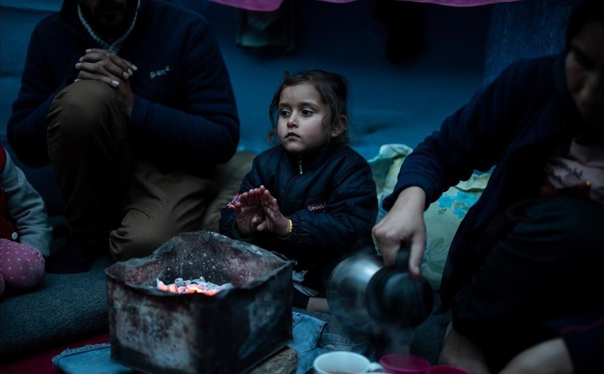 Marjan Hosini, de 3 años, calienta sus manos sobre el carbón caliente en su refugio temporal en un asentamiento improvisado junto al campamento de Moria, en Lesbos. Marjan Hosini, de 3 años, calienta sus manos sobre el carbón caliente en su refugio temporal en un asentamiento improvisado junto al campamento de Moria, en Lesbos.