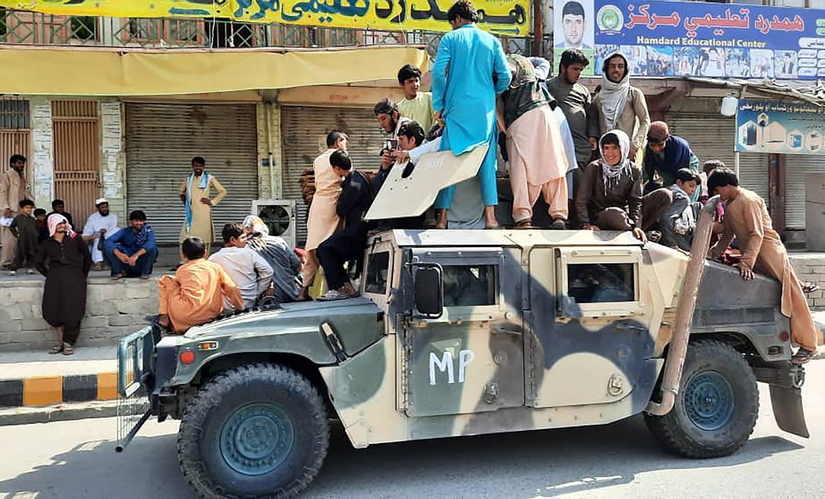 Un grupo de combatientes talibanes y residentes locales sube a un vehículo militar confiscado al ejército afgano en la provincia de Laghman. 