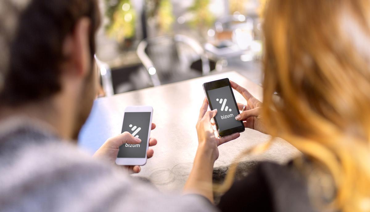 Dos usuarios usan la aplicación bizum en sus teléfonos móviles.