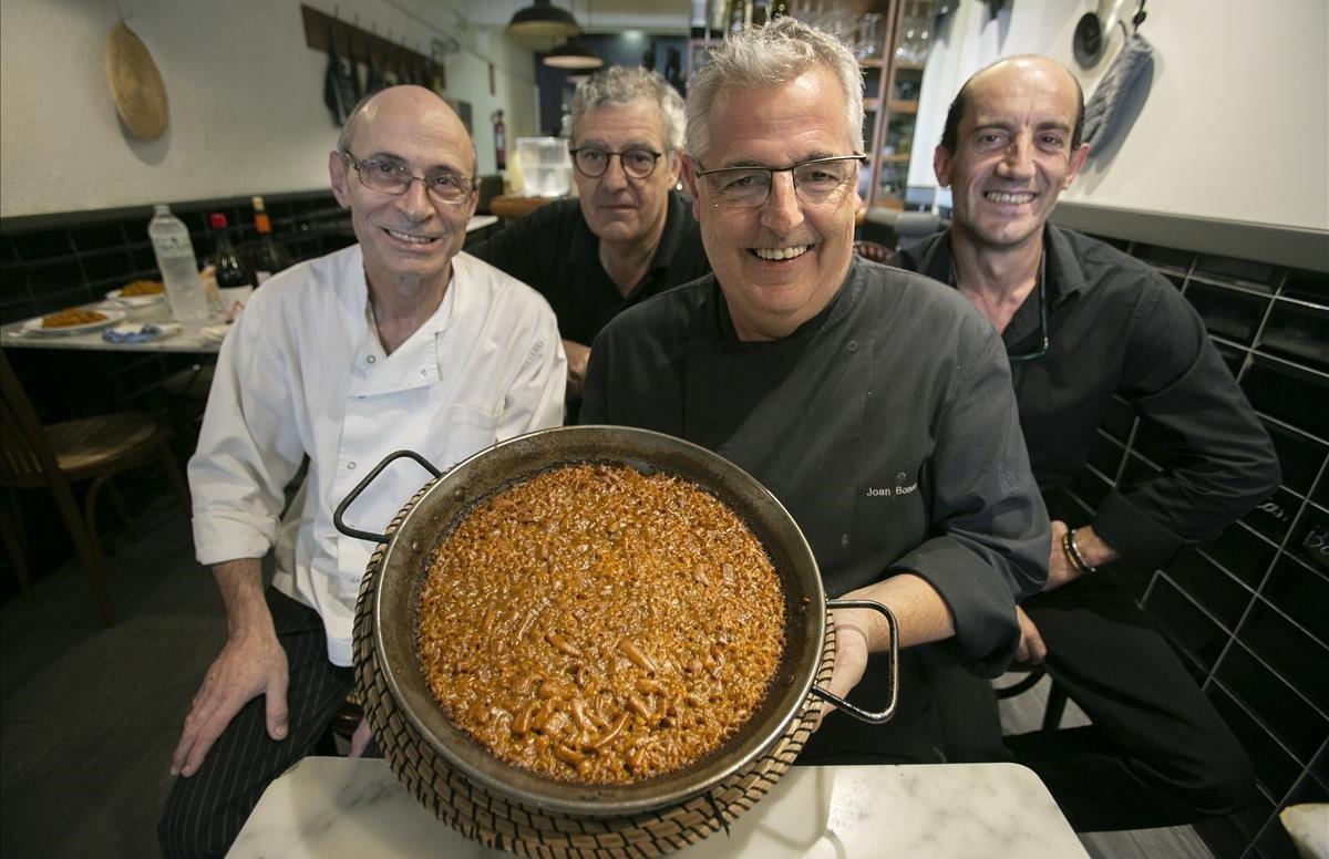 El dueño y chef de Can Boneta, Joan Boneta, muestra una paella acompañado de personal de su restaurante.