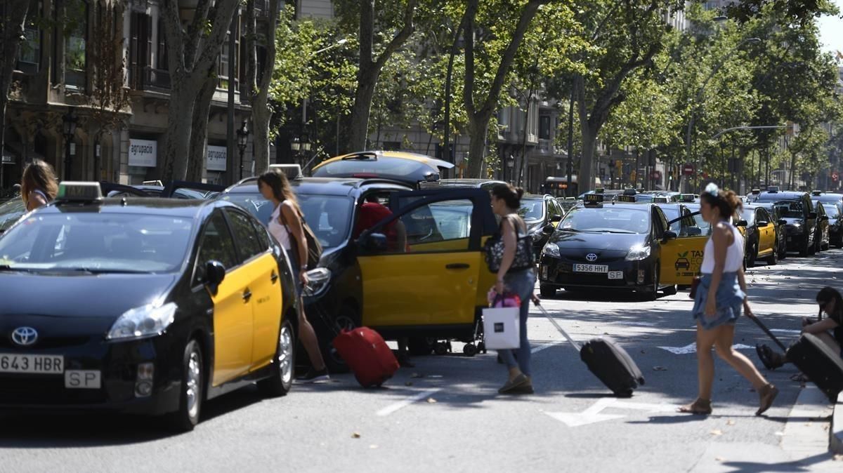 Turistas con maletas pasan entre los taxis parados. Turistas con maletas pasan entre los taxis parados.