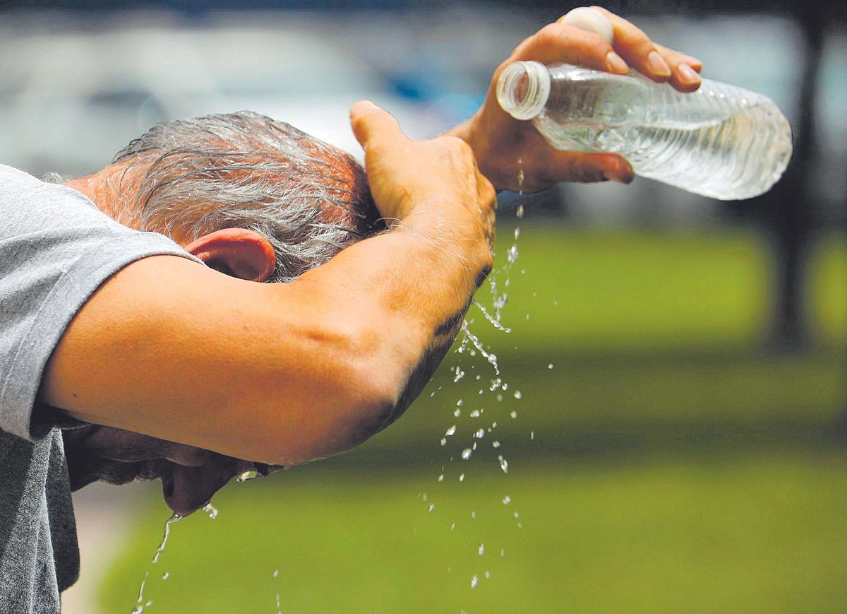 Un hombre trata de refrescarse de las altas temperatuas con una botella de agua. Un hombre trata de refrescarse de las altas temperatuas con una botella de agua.