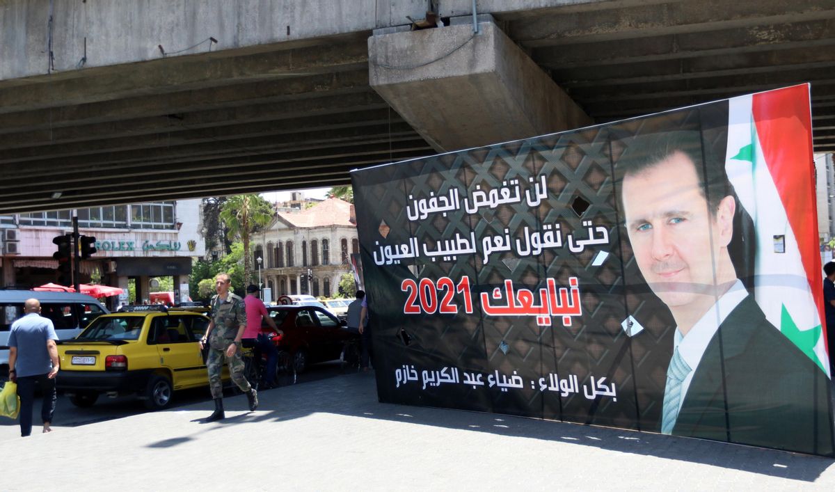 Varios peatones pasa junto a un cartel electoral que muestra al presidente sirio, Bachar Al Assad. Varios peatones pasa junto a un cartel electoral que muestra al presidente sirio, Bachar Al Assad.