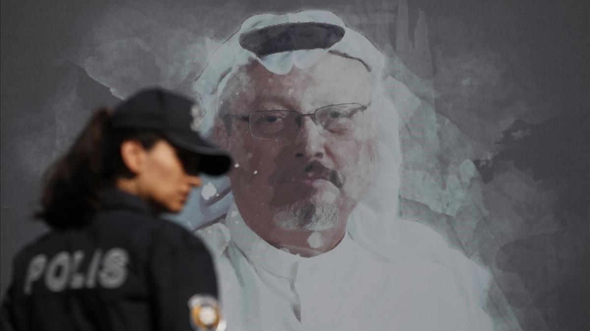 Una policía turca pasa frente una fotografía de Jamal Khashoggi en el acto en recuerdo del periodista asesinado celebrado en Estambul. Una policía turca pasa frente una fotografía de Jamal Khashoggi en el acto en recuerdo del periodista asesinado celebrado en Estambul.