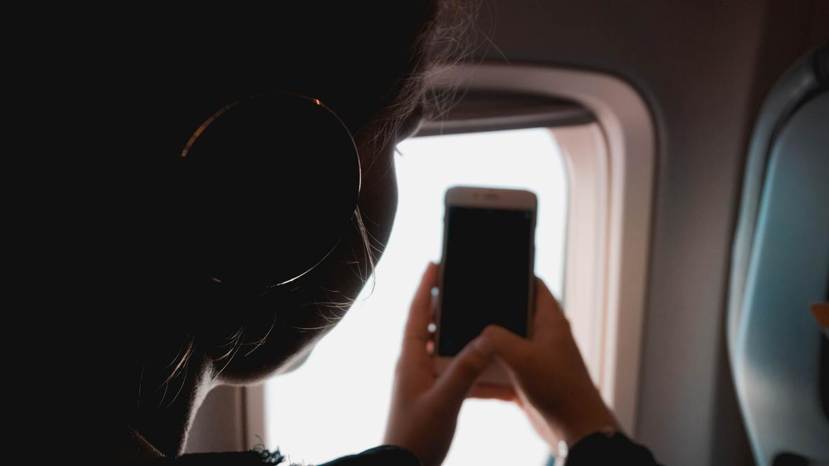 Una viajera usa el móvil en el avión