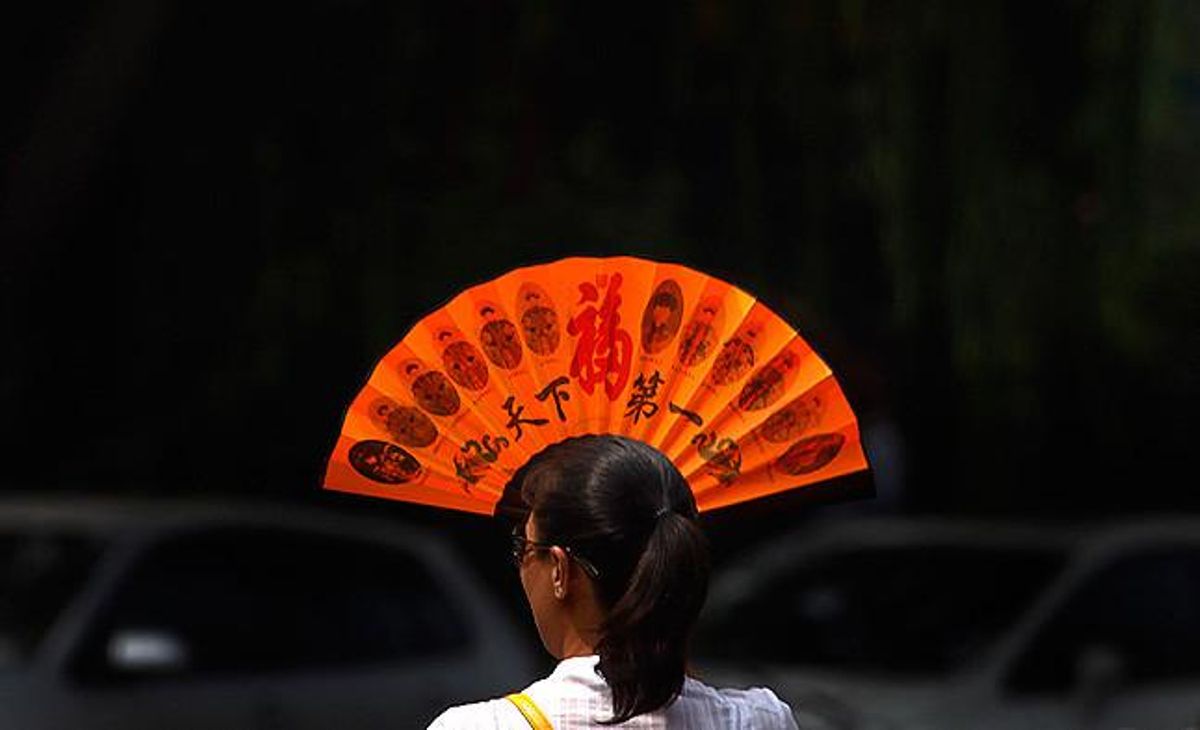 Una dona es tapa la cara amb un ventall per alleujar la calor en un carrer de Pequín. Una dona es tapa la cara amb un ventall per alleujar la calor en un carrer de Pequín.