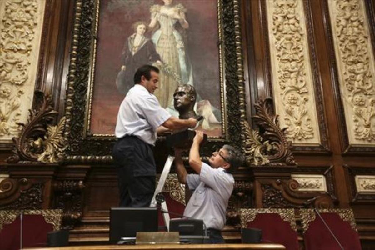 Operarios del Ayuntamiento de Barcelona retiran el busto del rey Juan Carlos del salón de plenos municipal antes de guardarlo en una caja de cartón.