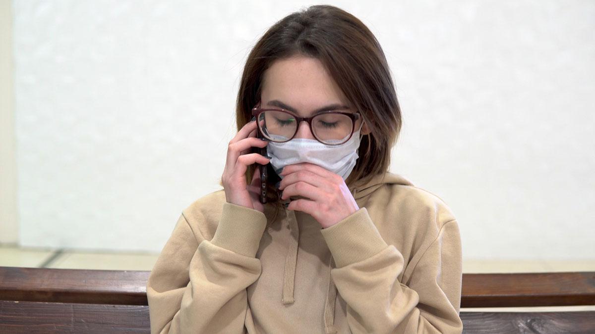 Una mujer tose mientras habla con el móvil.