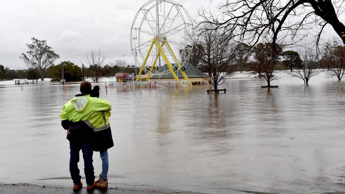 La gente mira un parque inundado debido a las lluvias torrenciales en el suburbio de Camden en Sydney , Australia.