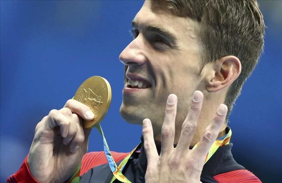 Phelps muestra su medalla señalando los cuatro oros que ha conseguido hasta ahora Phelps muestra su medalla señalando los cuatro oros que ha conseguido hasta ahora