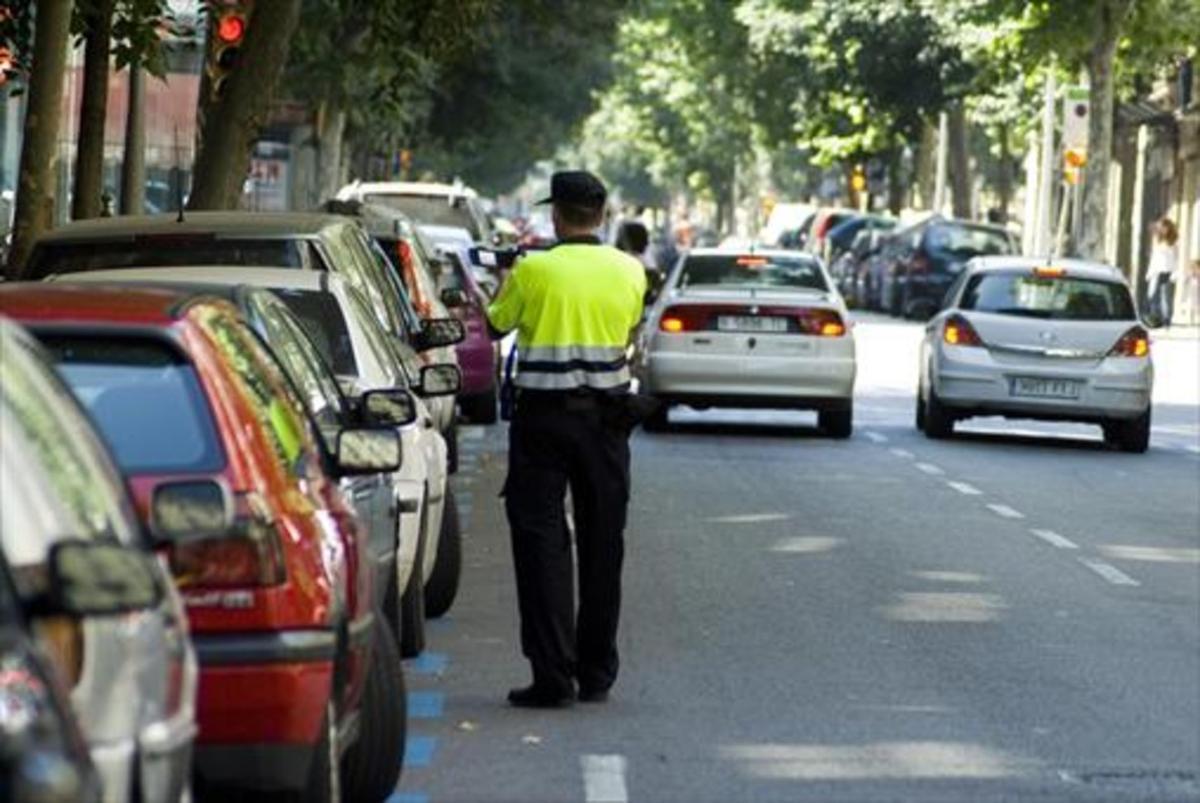 Un empleado de BSM impone una sanción a un vehículo aparcado en el área azul de la calle de Girona.