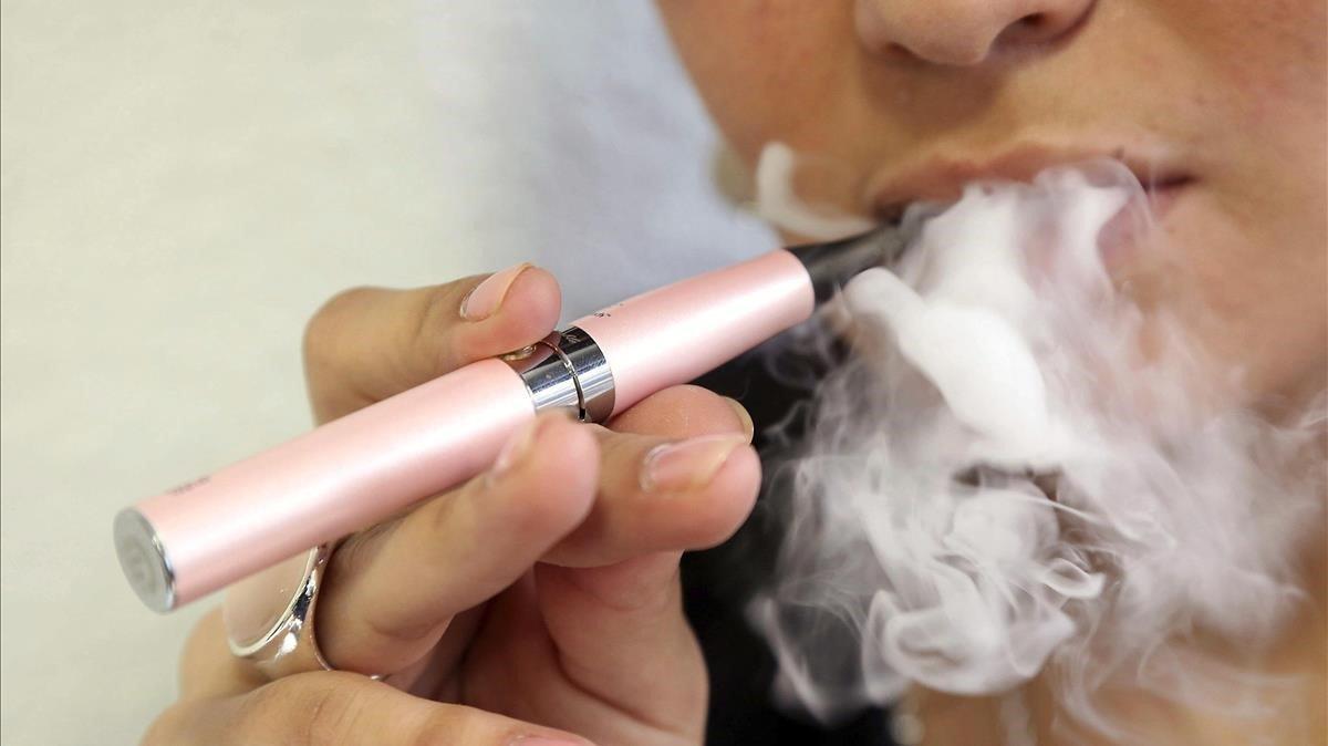 Una mujer fuma un cigarrillo electrónico. Una mujer fuma un cigarrillo electrónico.