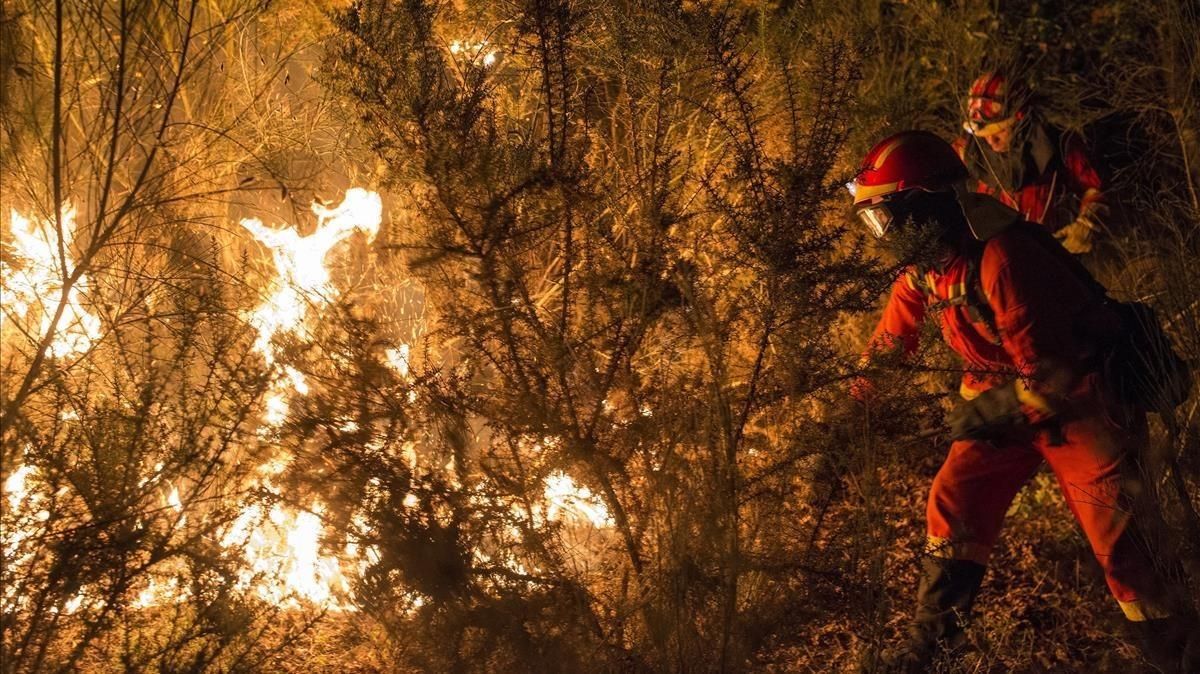 Unos bomberos luchan contra el fuego en Vilamarin, en Galicia. Unos bomberos luchan contra el fuego en Vilamarin, en Galicia.