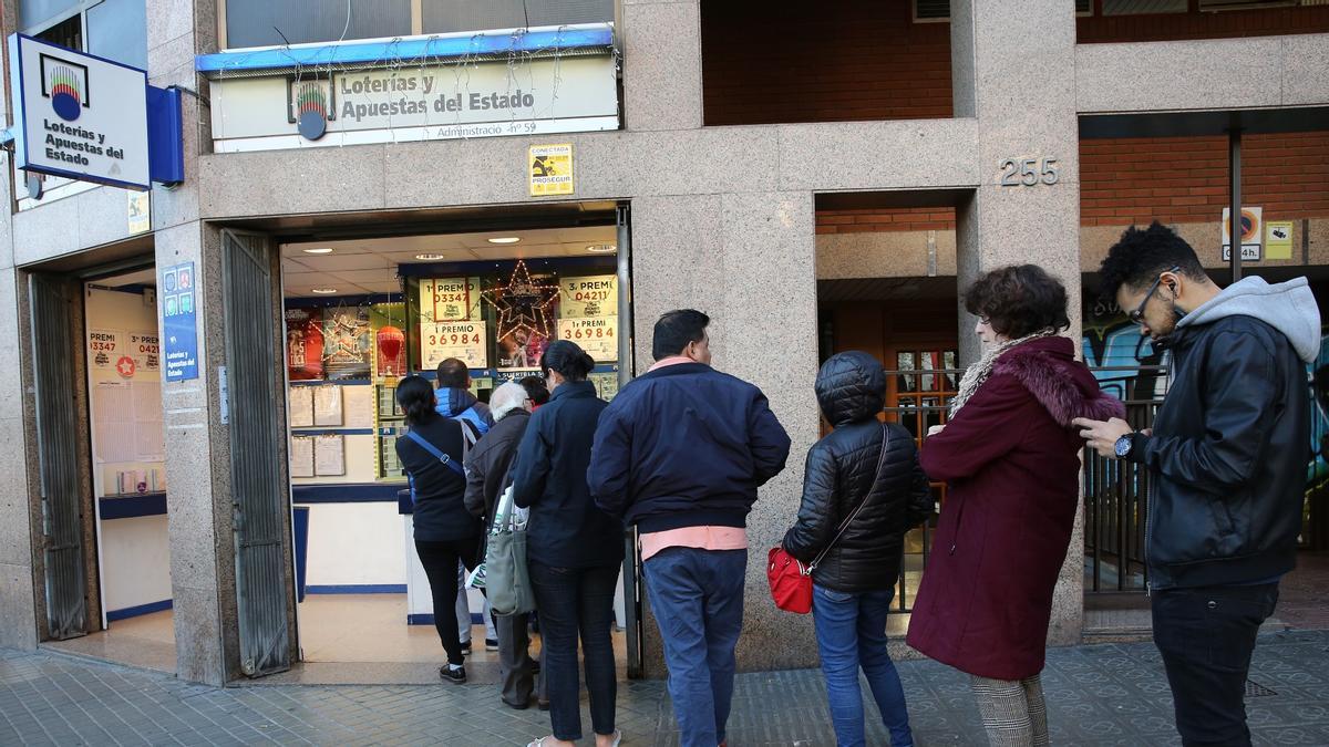 Varias personas hacen cola para comprar Lotería de Navidad en una administración de Barcelona.