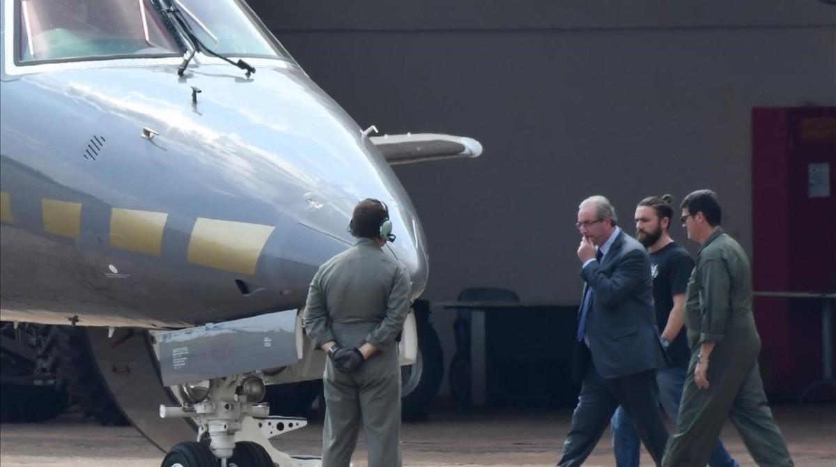 Eduardo Cunha camina luego de ser detenido hacia un avion de la Policía Federal.