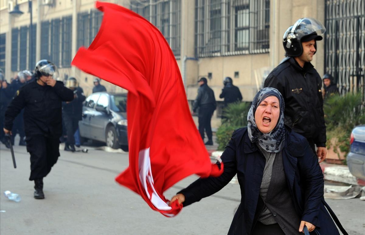 Una mujer tunecina muestra la bandera de su país frente al Ministerio del Interior, durante los enfrentamientos entre los manifestantes y fuerzas de seguridad en Túnez, el 14 de enero del 2011.