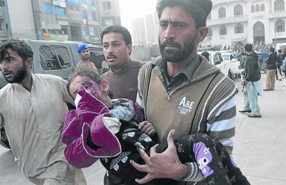 Un hombre traslada a una niña herida en el asalto del comando talibán a una escuela en Peshawar.