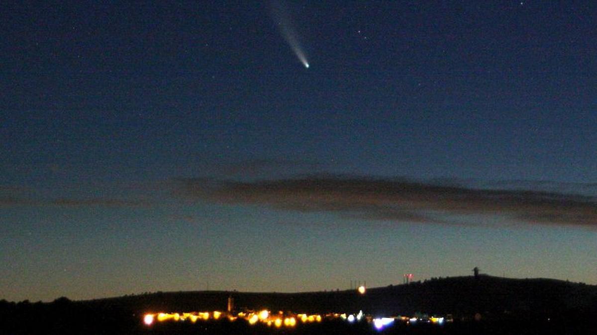 El cometa Neowise, fotografiado encima de un centro habitado fuertemente iluminado. El cometa Neowise, fotografiado encima de un centro habitado fuertemente iluminado.