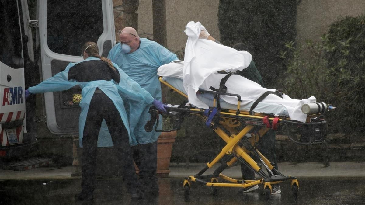 Un equipo de sanitarios traslada a un paciente, en medio de una fuerte lluvia, en Kirkland, en el estado de Washington. Un equipo de sanitarios traslada a un paciente, en medio de una fuerte lluvia, en Kirkland, en el estado de Washington.
