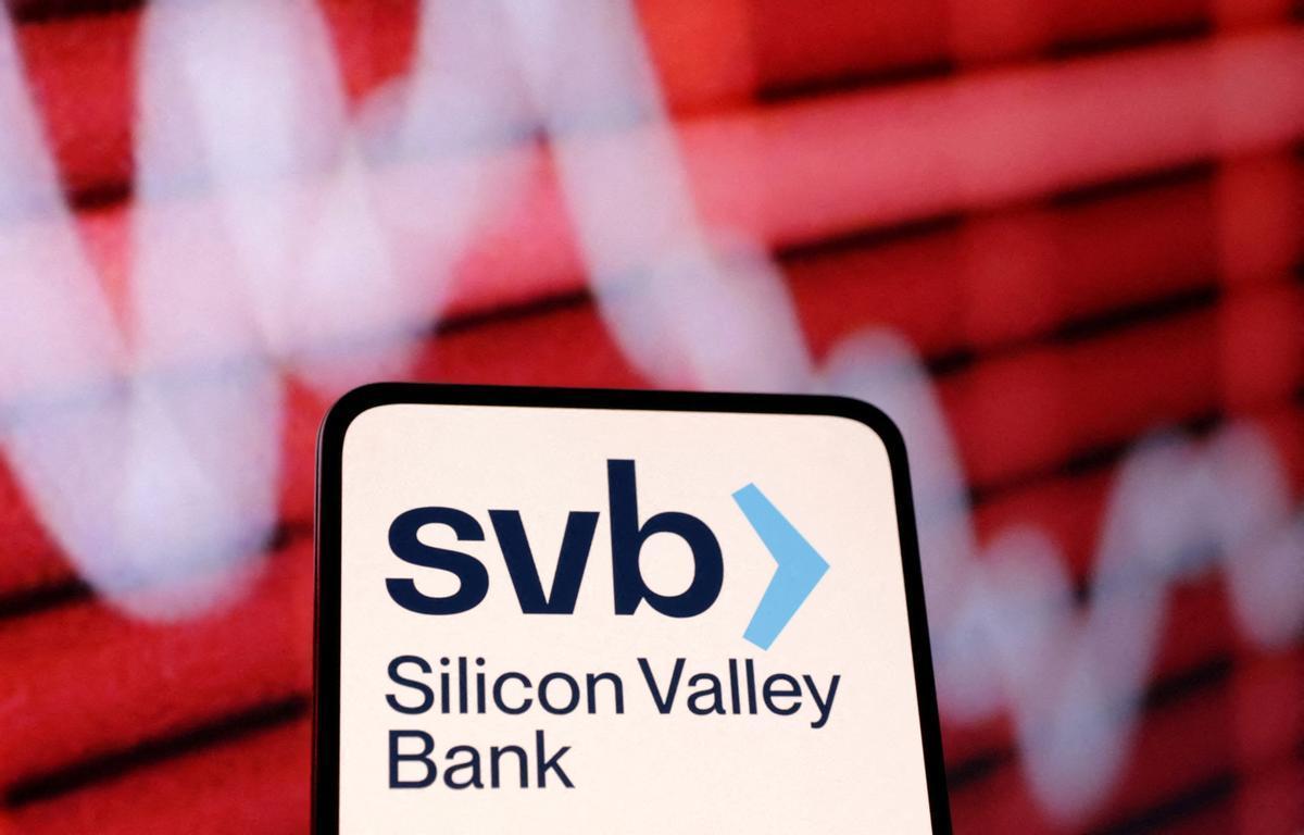 El logo de SVB en un teléfono móvil y junto a un panel.