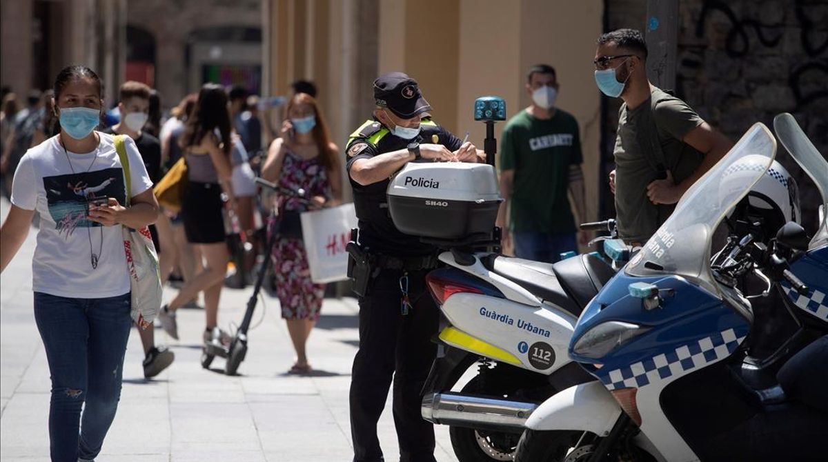 Un policía extiende una multa a un ciudadano en una calle de Barcelona, el verano pasado. Un policía extiende una multa a un ciudadano en una calle de Barcelona, el verano pasado.