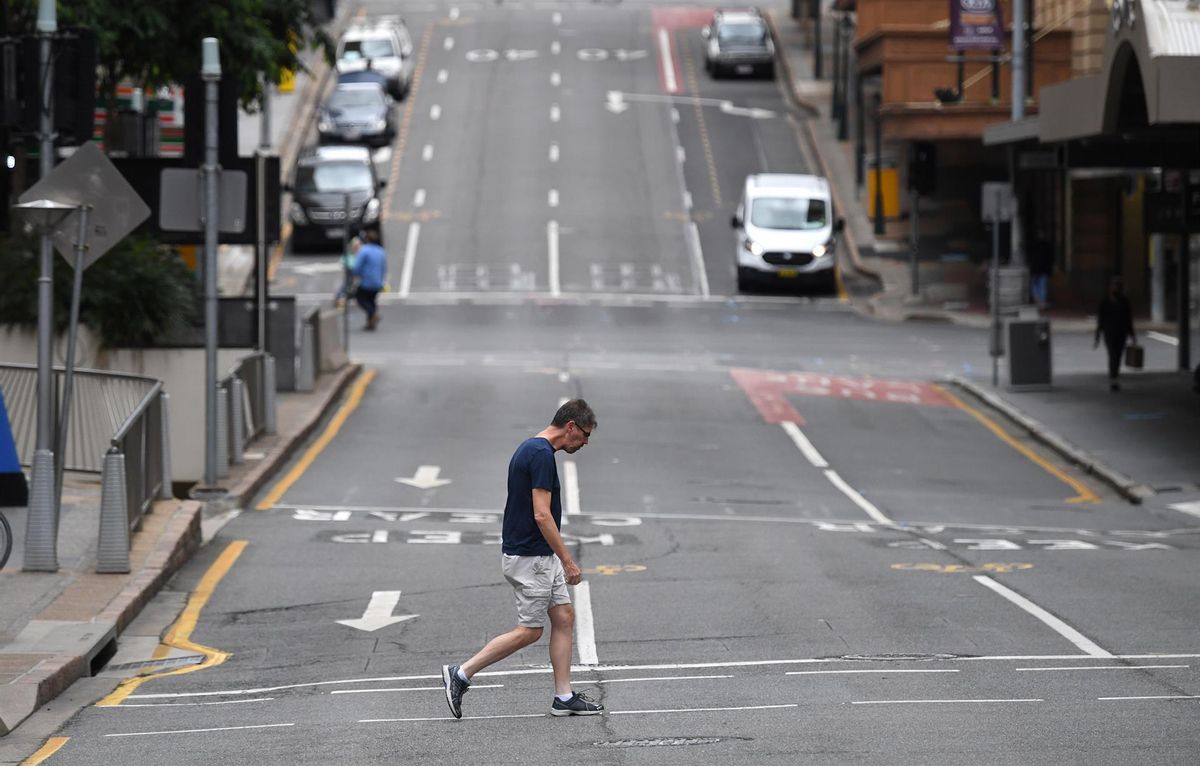 Un hombre cruza una calle casi vacía en Brisbane. Un hombre cruza una calle casi vacía en Brisbane.