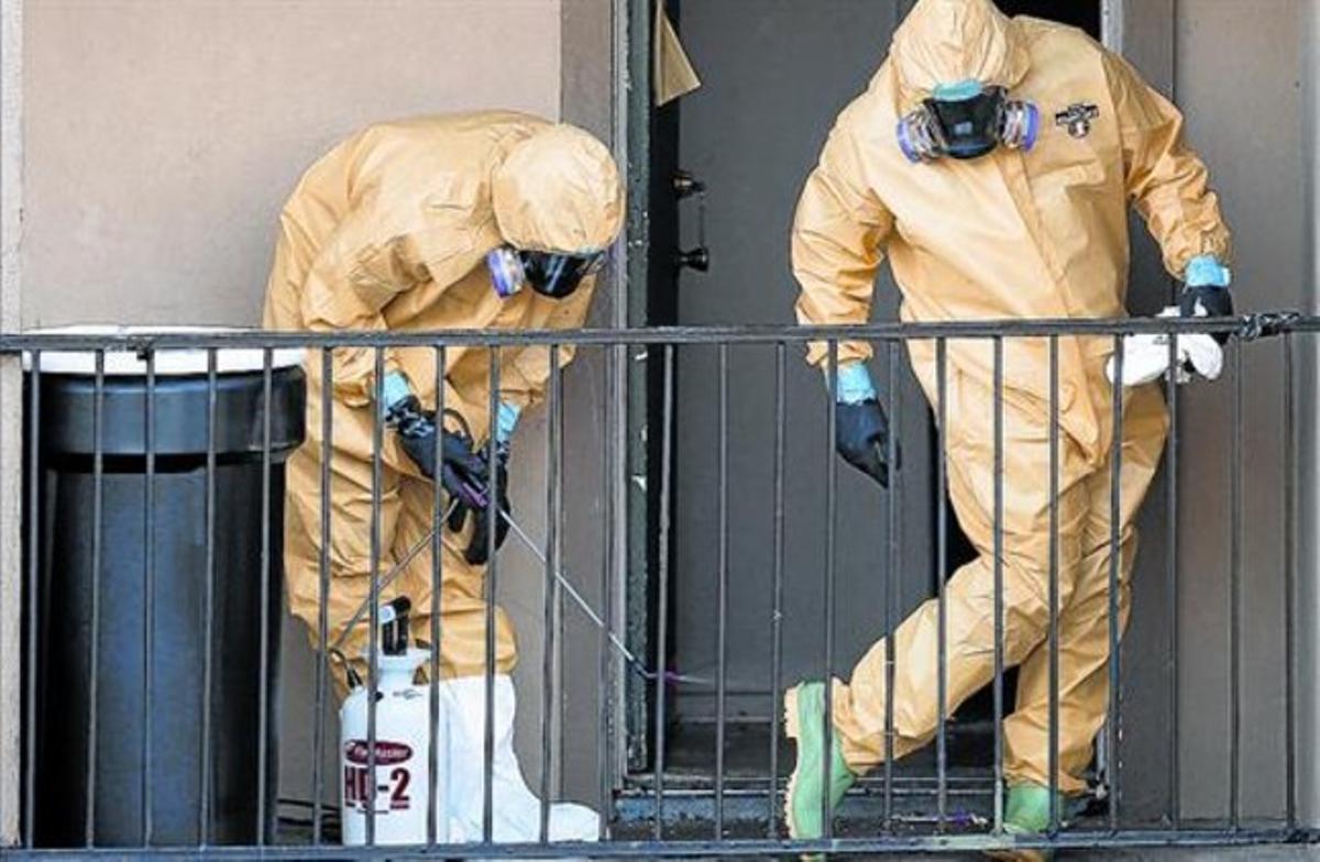 Dos trabajadores limpian sus trajes tras vaciar el apartamento del hombre al que se diagnosticó ébola en Dallas.