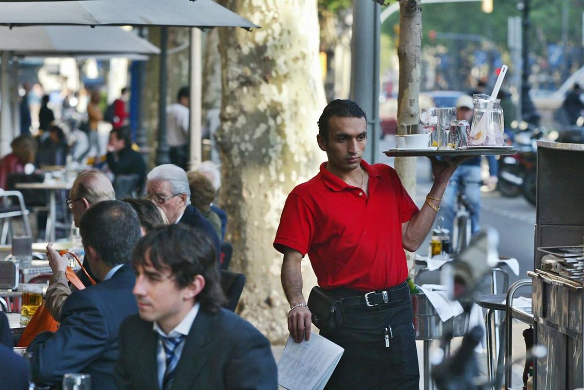 Un camarero trabajando en una terraza de un bar del Passeig de Gràcia de Barcelona. Un camarero trabajando en una terraza de un bar del Passeig de Gràcia de Barcelona.