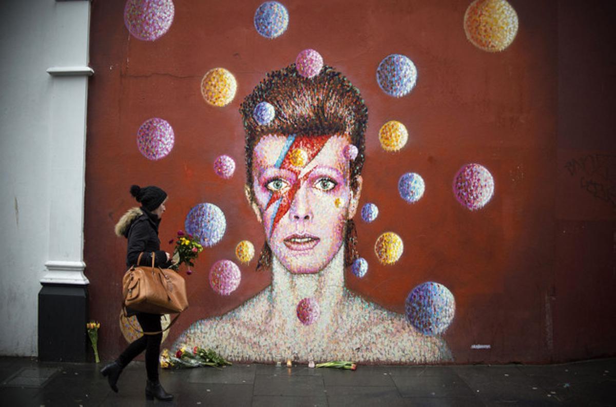 Flores ante un mural de David Bowie en la pared del comercio Morley, en Brixton (Londres), lugar de nacimiento del cantante. 
