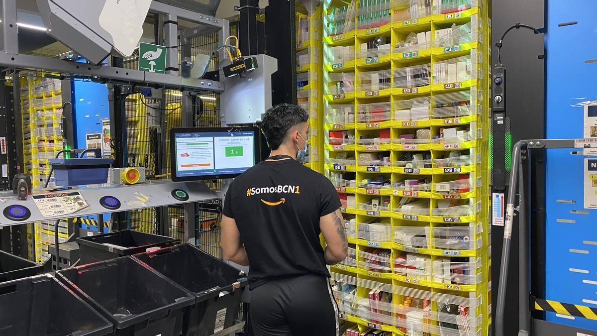 Un empleado de Amazon incorpora productos al almacén de Amazon en El Prat