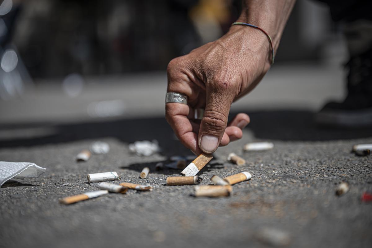 Una persona recoge una colilla de cigarrillo tirada en el suelo de Barcelona. 