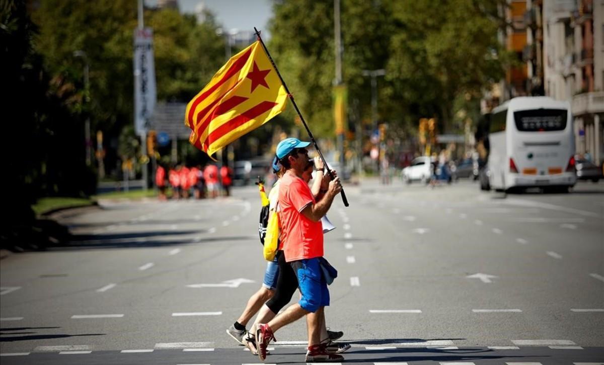Dos ciudadanos con ’estelades’ cruzan una calle en Barcelona horas antes de la manifestación de la Diada.