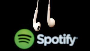 Unos auriculares ante un logo de Spotify