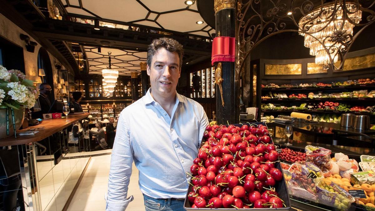 Marc Taribó, dueño de Camarasa Fruits, con una bandeja de cerezas que venden en la barra de la entrada al nuevo establecimiento de la plaza de Francesc Macià.