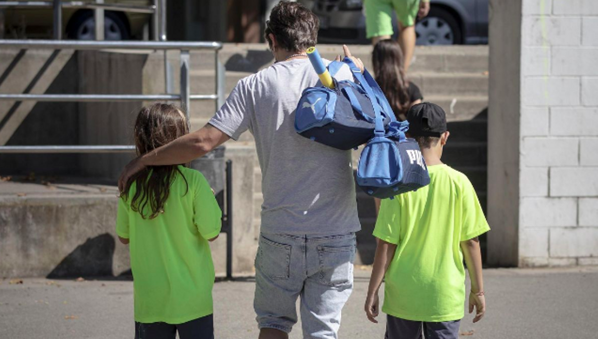 Un padre acompaña a sus hijos a jugar a tenis, en Barcelona.