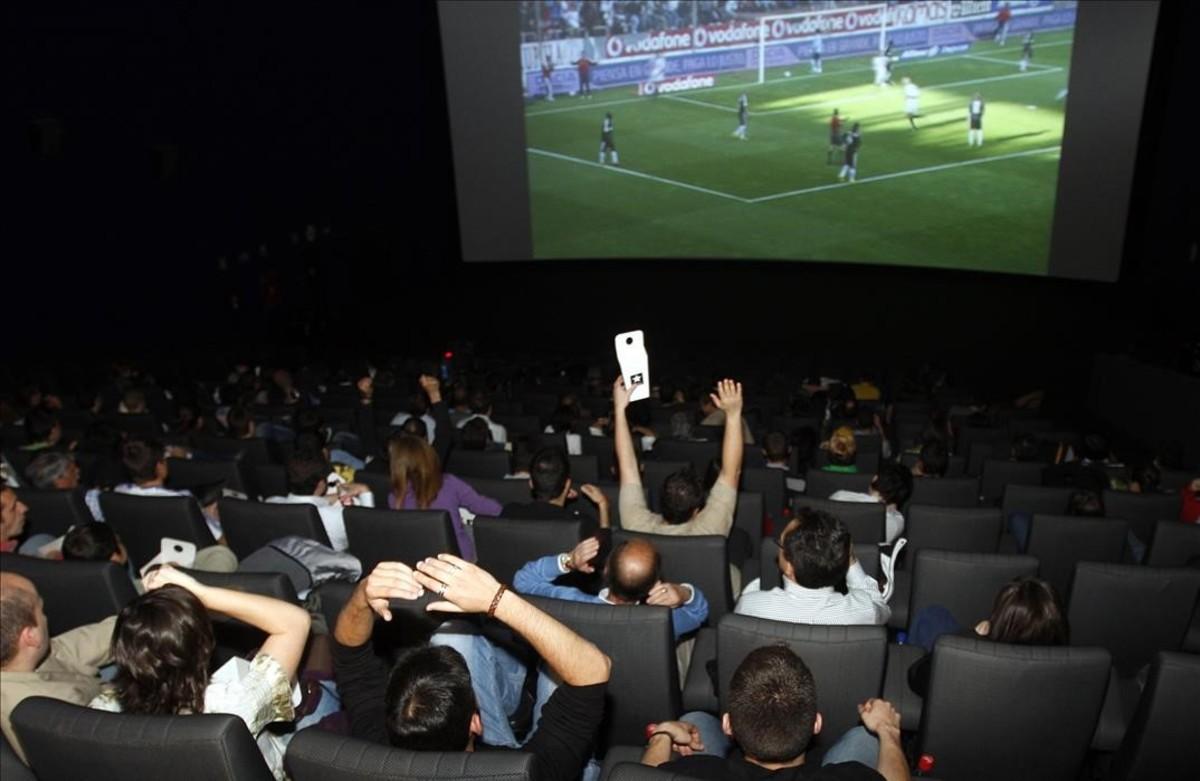 Aficionados siguiendo un partido de fútbol televisado en un cine madrileño.