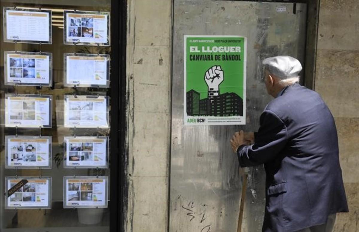 Un hombre observa un cartel de la manifestación contra los precios de los alquileres.
