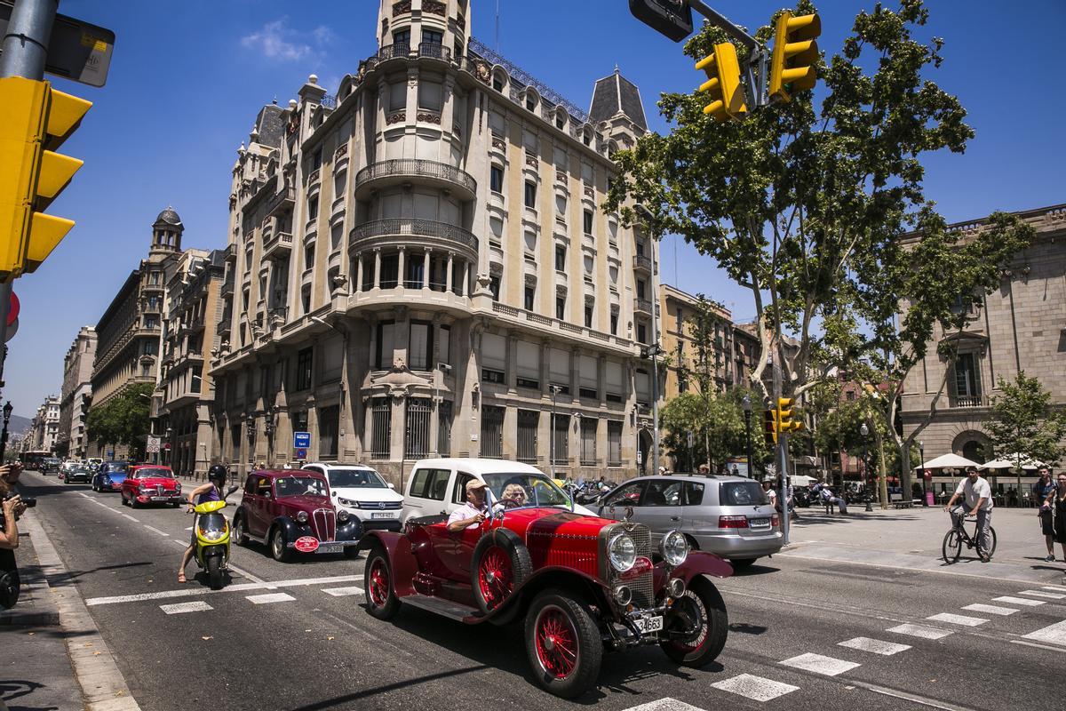 Vehículos de época se mezclan con motos y coches actuales en la Via Laietana de Barcelona.