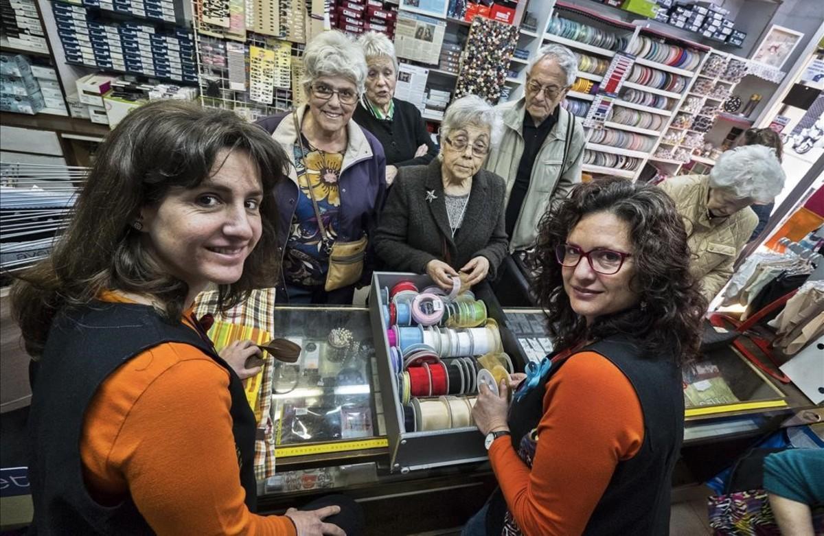 Las hermanas Glòria  (izquierda) y Raquel  Rivero, al frente de  la mercería Esmar, con buena parte de la clientela mayor.