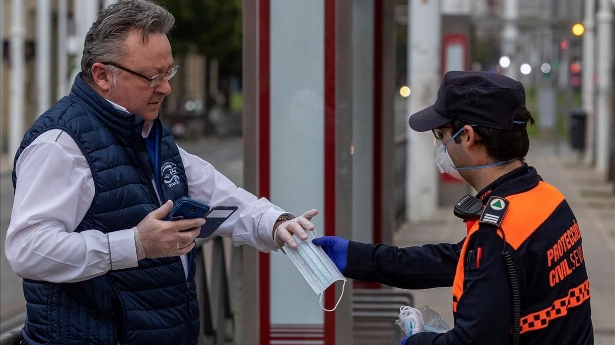 Un voluntario de Proteccion Civil repartiendo mascarillas a los viajeros de los autobuses urbanos de Sevilla Un voluntario de Proteccion Civil repartiendo mascarillas a los viajeros de los autobuses urbanos de Sevilla