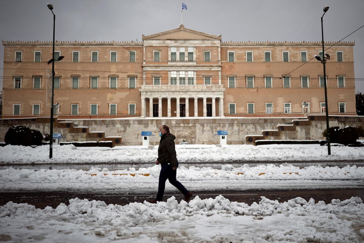 Un hombre con mascarilla camina frente al edificio del Parlamento griego, en Atenas.
